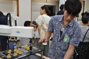 お菓子つかみロボットを説明する学生の写真